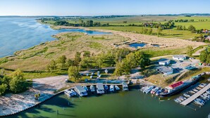An aerial view of a marina with boats docked, a small dock, and a grassy area with trees. - Beautiful ship in Sagard with sauna (Sagard)