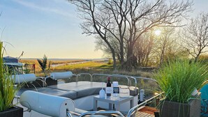 A deck with outdoor seating, a bottle of wine, and a menu. - Beautiful ship in Sagard with sauna (Sagard)