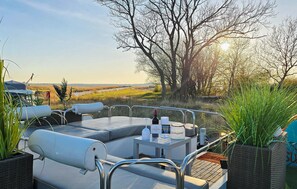 A deck with outdoor seating, a bottle of wine, and a menu. - Beautiful ship in Sagard with sauna (Sagard)