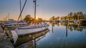 A marina with several boats docked, calm water, and a sunset in the background. - Beautiful ship in Sagard with sauna (Sagard)