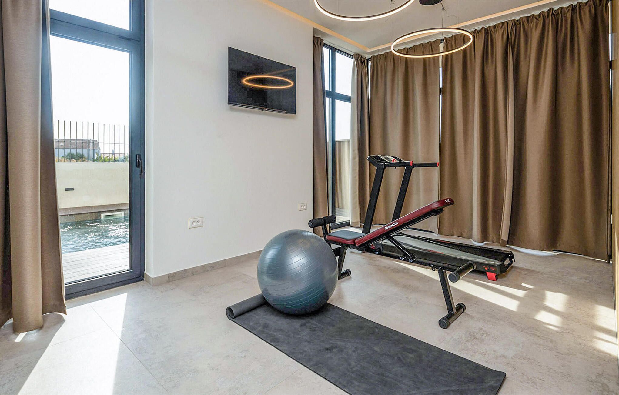 Un gimnasio en casa con equipo de ejercicio, una pelota grande para ejercicio y una cinta de correr.