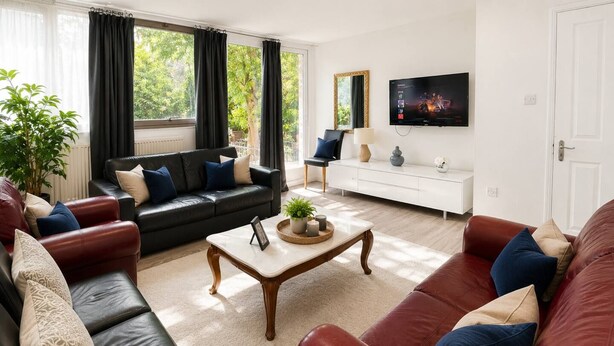 Una sala de estar moderna con un sofá de cuero negro, un sofá de cuero rojo, una mesa de centro de madera y una consola blanca.