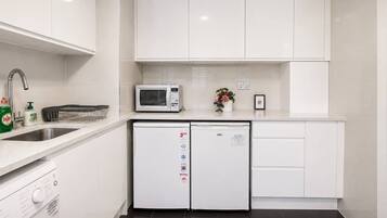 Een moderne keuken met witte kastjes, een magnetron, een vaatwasser en een spoelbak.