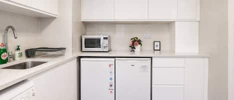 Una cocina moderna con armarios blancos, un microondas, un lavavajillas y un fregadero.
