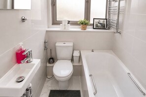 A modern bathroom with a toilet, bidet, and bathtub.