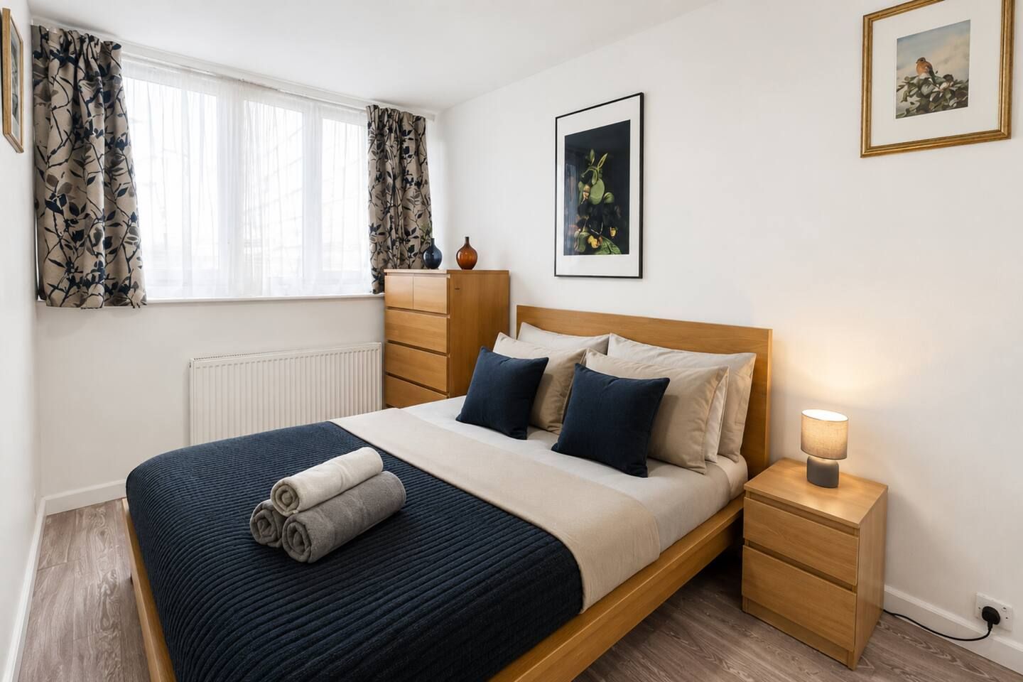 Een slaapkamer met een bed, nachtkastje en een nachttafeltje met een lamp.
