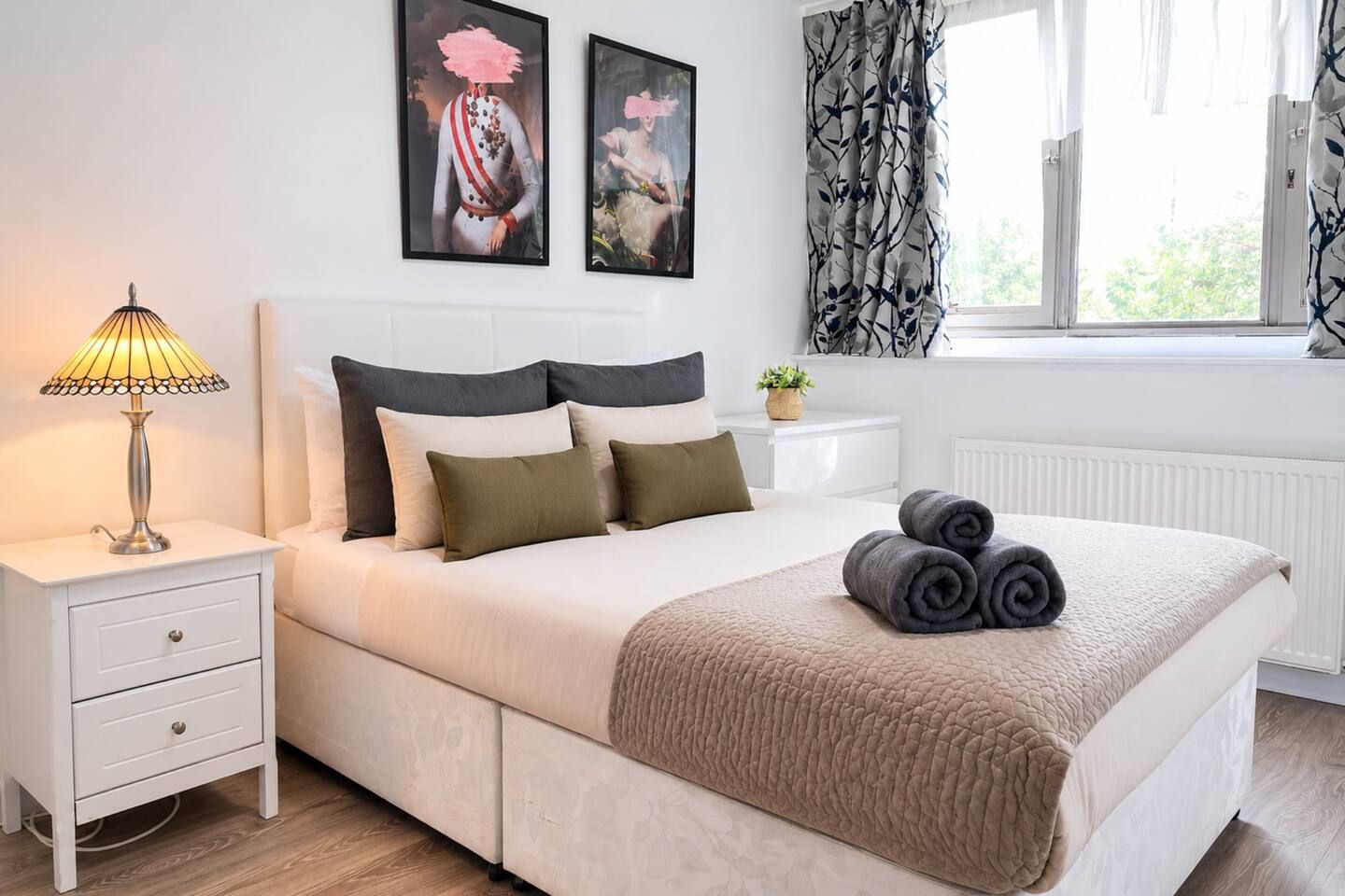 Un lit bien fait, recouvert d’une courtepointe beige, une lampe de chevet et une table de chevet avec un tiroir.