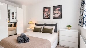 Un dormitorio moderno con una cama, mesitas de noche, una lámpara y obras de arte en la pared.