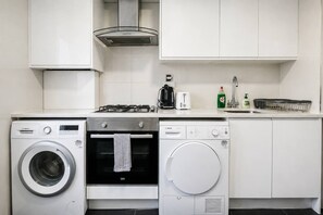 Una cocina con lavadora Bosch, horno Bosch, lavavajillas Bosch, estufa a gas y cafetera.