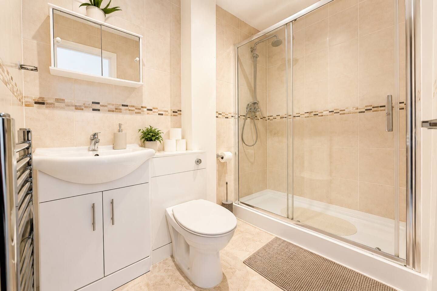 Un bagno con doccia vetrata, un lavandino bianco con specchio sopra e un water.