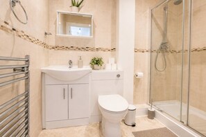 Une salle de bain avec une douche à parois de verre, un lavabo blanc et des toilettes.