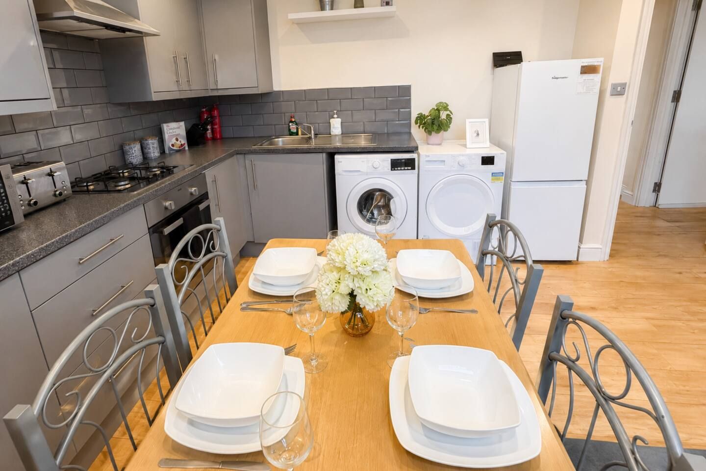 A modern kitchen with grey cabinets, a stainless steel sink, a built-in oven, and a dishwasher.