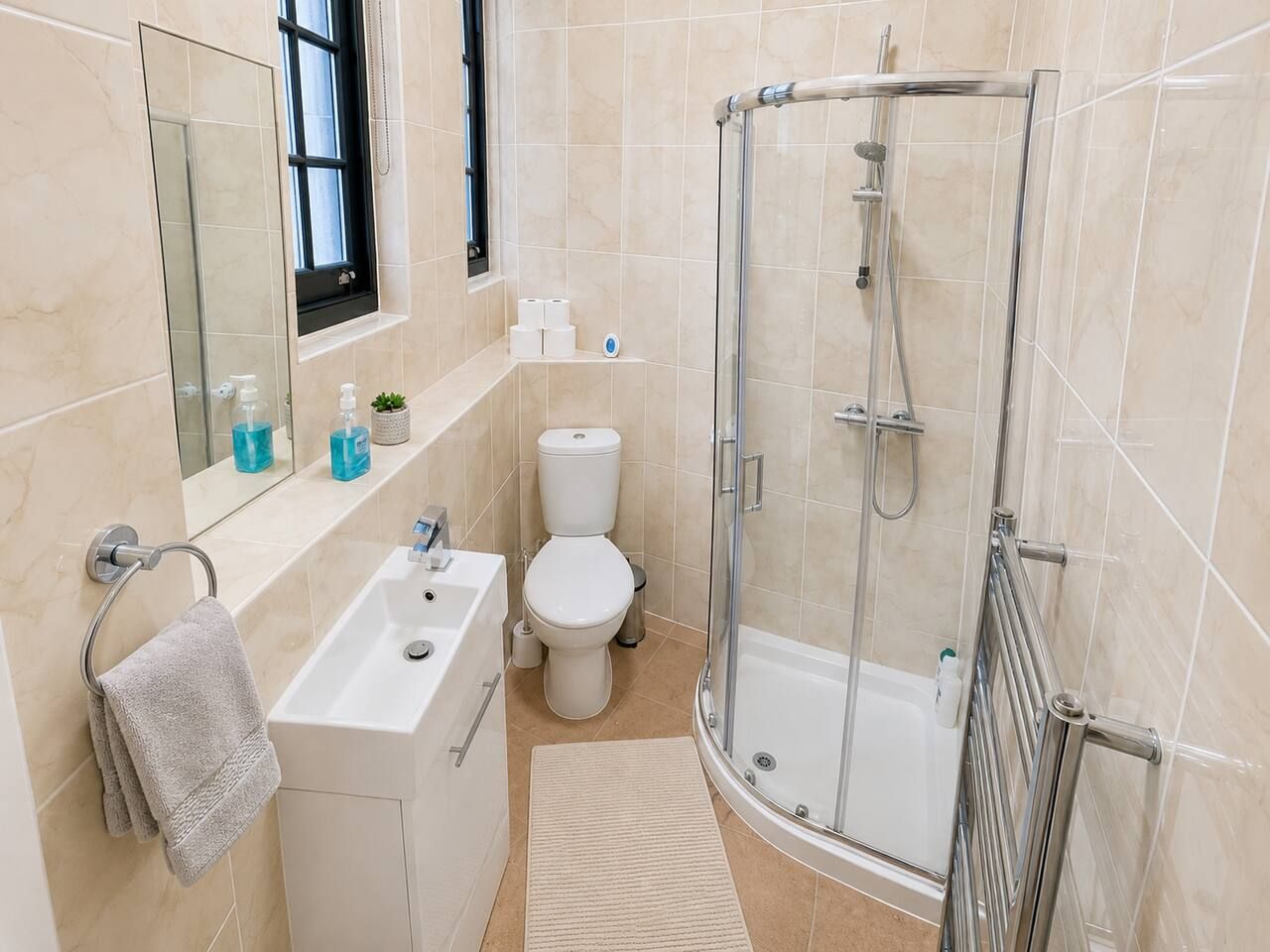 A modern bathroom with a glass-enclosed shower, a white sink, and a toilet.