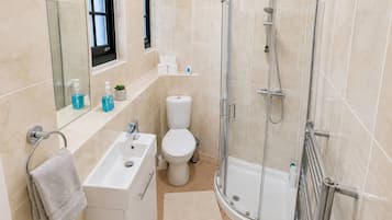 A modern bathroom with a glass-enclosed shower, a white sink, and a toilet.