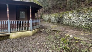 Una cabaña rústica con porche y pared de piedra.
