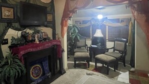 Una sala de estar con chimenea, televisor y dos sillones.