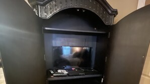 Un mueble multimedia negro con un televisor de pantalla plana, un reproductor de DVD y un equipo de sonido estéreo.