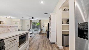 Eine moderne Küche mit weißen Schränken, einem Edelstahlkühlschrank und einem Essbereich mit Tisch und Stühlen.