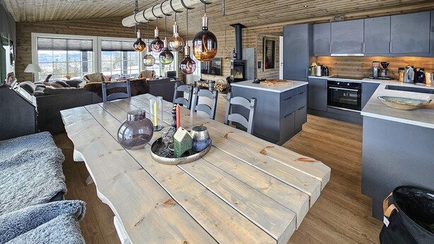 A modern kitchen with grey cabinets, a central island, and a dining area with a wooden table and chairs. - Stunning home in Eggedal with WiFi (Eggedal)