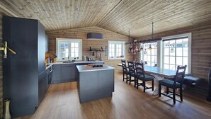 A modern kitchen with a central island, wooden ceiling, and large windows providing natural light. - Stunning home in Eggedal with WiFi (Eggedal)