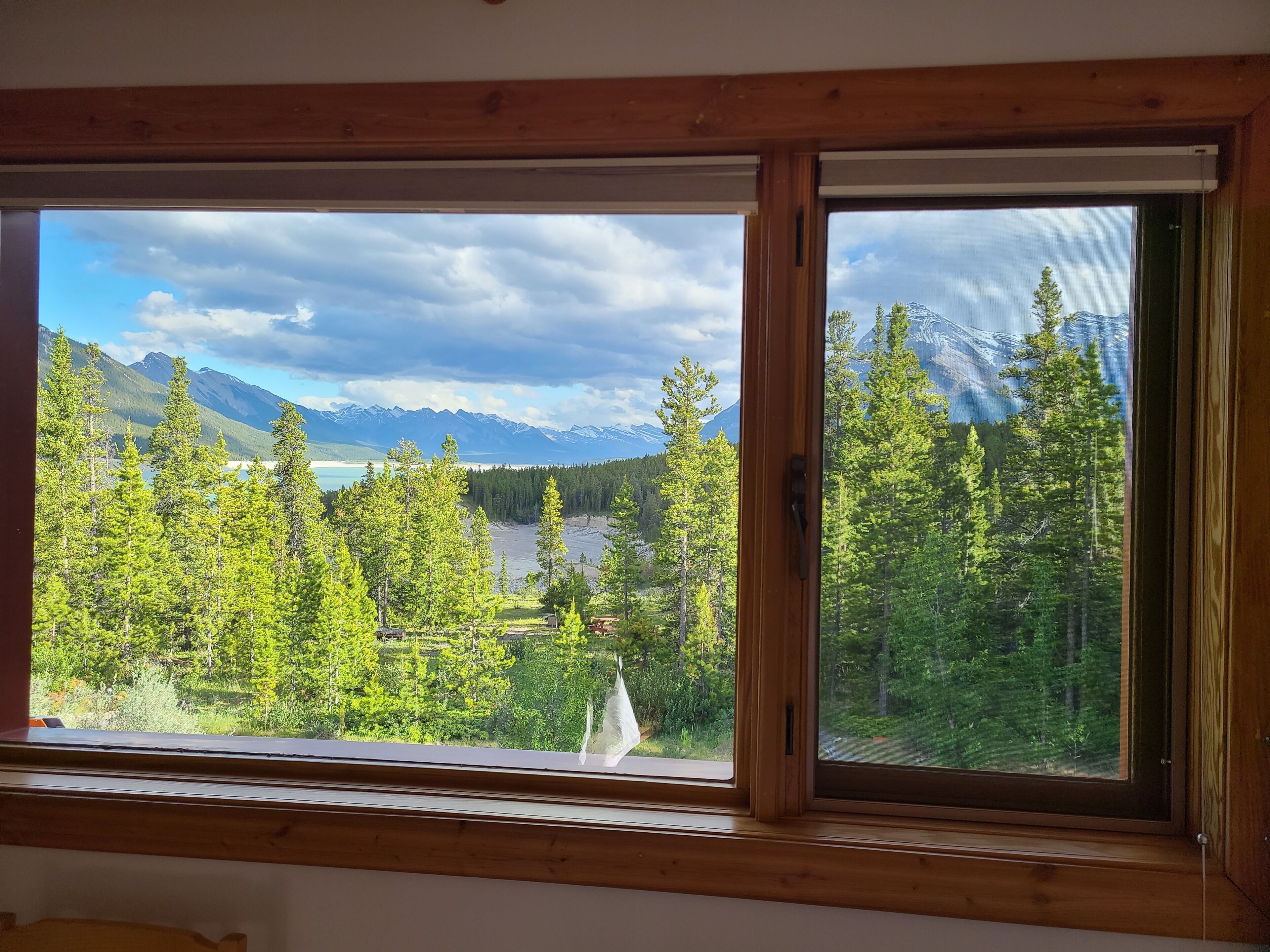A room with a large window offering a view of a mountainous landscape with trees and a lake.