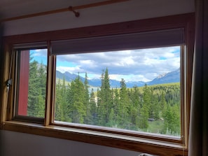 A room with a large window offering a view of a forest and mountains. - Aurum Lodge (Cline River)
