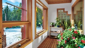A wooden-paneled room with large windows, a wooden ceiling, and a view of a snowy landscape. - Aurum Lodge (Cline River)