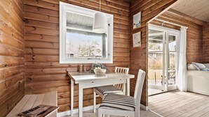 A wooden cabin interior with a dining area, white furniture, and a view through a window. - Beautiful home in Frederiksværk (Frederiksværk)