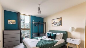 Une chambre d’hôtel moderne équipée d’un lit, d’un bureau, d’une chaise et d’un balcon offrant une vue sur la ville.