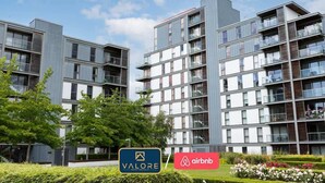 Un immeuble d’appartements moderne doté de balcons, une enseigne indiquant « Valore Property Services » et le logo d’Airbnb.