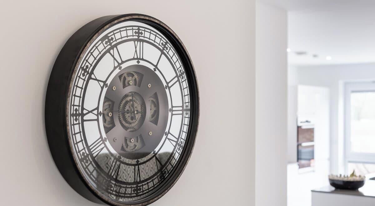 A wall-mounted clock with Roman numerals and gears.