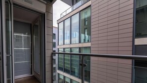 Een modern gebouw met balkon, grote ramen en een metalen hekwerk.
