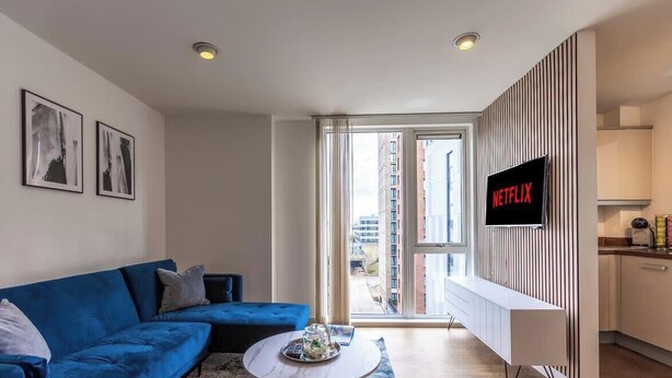 Een moderne woonkamer met een blauwe bank, een salontafel en een tv waarop 'NETFLIX' staat.