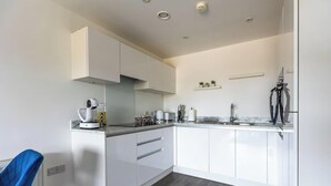 Een moderne keuken met witte kasten, een koffieapparaat en een magnetron.