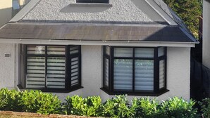 Ein Haus mit steiler Satteldachform, weißen Außenwänden und schwarzen Fensterrahmen.