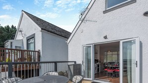 Ein modernes Haus mit Terrasse, Essbereich und durch Glastüren sichtbarer Küche.