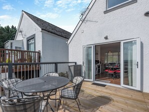 A modern house with a patio, a dining area, and a kitchen visible through glass doors.
