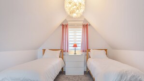 Ein Schlafzimmer mit zwei Einzelbetten, einem Schreibtisch, einer Lampe und einer Deckenleuchte.