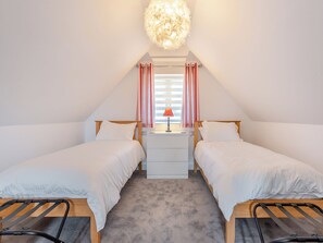A bedroom with two single beds, a desk, a lamp, and a ceiling light fixture. - 2 bedroom accommodation in Goodwick (Goodwick)