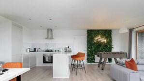 A modern kitchen with white cabinets, a central island, and a foosball table.