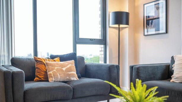 A modern living room with two dark grey sofas, a floor lamp, and a framed picture on the wall. - Modern, Spotless & Close to City Hotspots! (Greater Manchester)