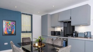 A modern kitchen with grey cabinets, a black microwave, and a kettle on the counter. - Modern, Spotless & Close to City Hotspots! (Greater Manchester)