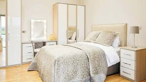 Ein Schlafzimmer mit einem Bett, Nachttischen, einem Kleiderschrank und einem Spiegel.