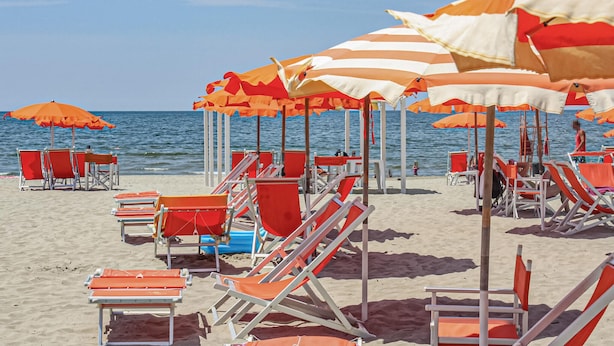 A beach with rows of orange and white striped umbrellas and red lounge chairs. - Awesome apartment in Verni (LU) with WiFi (Verni)