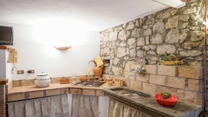 A rustic kitchen with a stone wall, a gas stove, and various kitchen utensils. - Awesome apartment in Verni (LU) with WiFi (Verni)