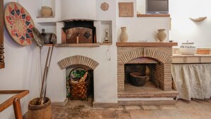 A rustic kitchen with a brick oven, a woven basket, and various pottery items. - Awesome apartment in Verni (LU) with WiFi (Verni)