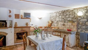 A rustic kitchen with a stone wall, a fireplace, and a dining area with a table set for four. - Awesome apartment in Verni (LU) with WiFi (Verni)