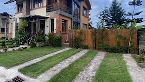 A two-story house with a stone facade, a balcony, and a well-maintained lawn with stone pathways.