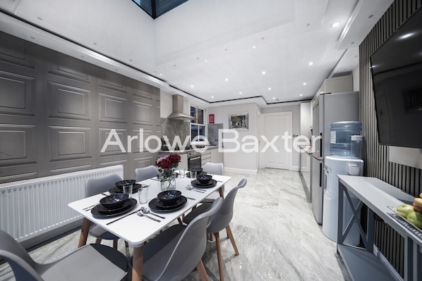 A modern kitchen with a built-in stove, a water dispenser, and a large white cabinet.