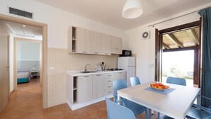A compact kitchen with white cabinets, a sink, and a dining area with blue chairs.